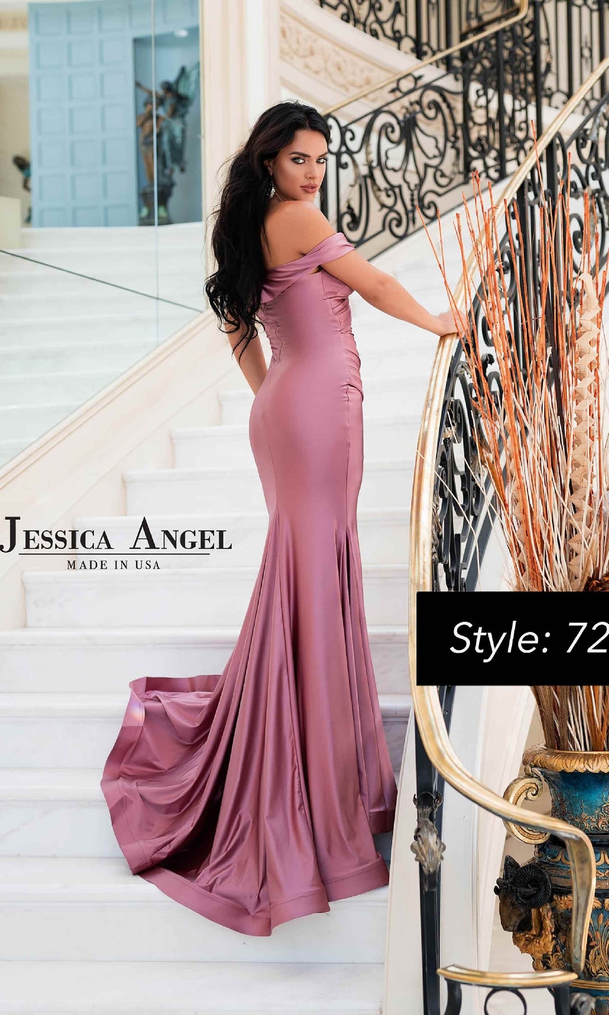 A woman in a mauve Criss-Cross Long Prom Dress by Jessica Angel (Style 721) stands on a white staircase, looking over her shoulder. The off-the-shoulder gown features a dramatic train for an elegant formal look.